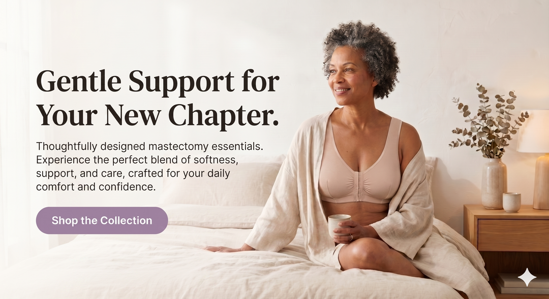 dark haired woman sitting on her bed in a cream dressing gown wearing a nude mastectomy bra