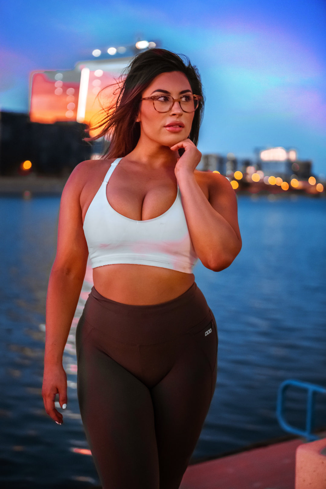 young woman with dark hair wearing a white sports bra and black jogging trousers s